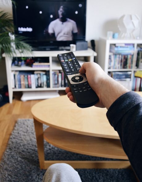 Photo of a young man switching channel on tv